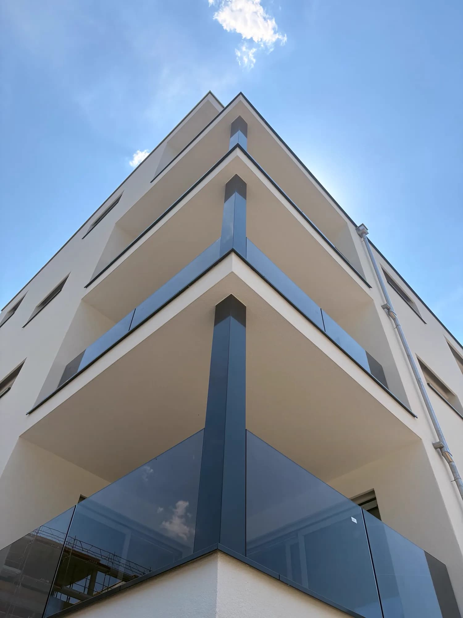 Angle d'un immeuble neuf, trois niveaux de garde-corps en verre fumé, chantier terminé